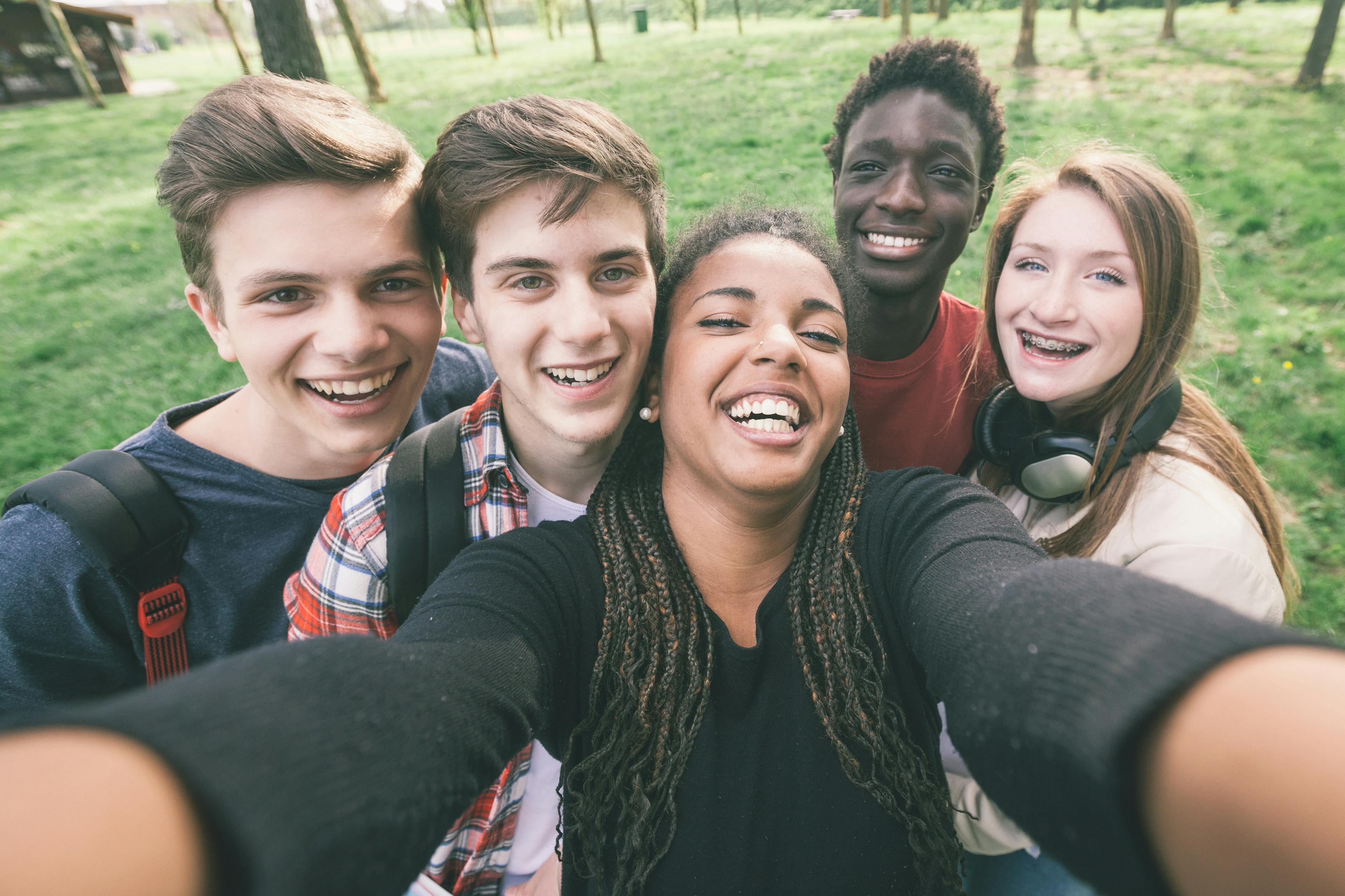A diverse group of young people smiling and taking a selfie together