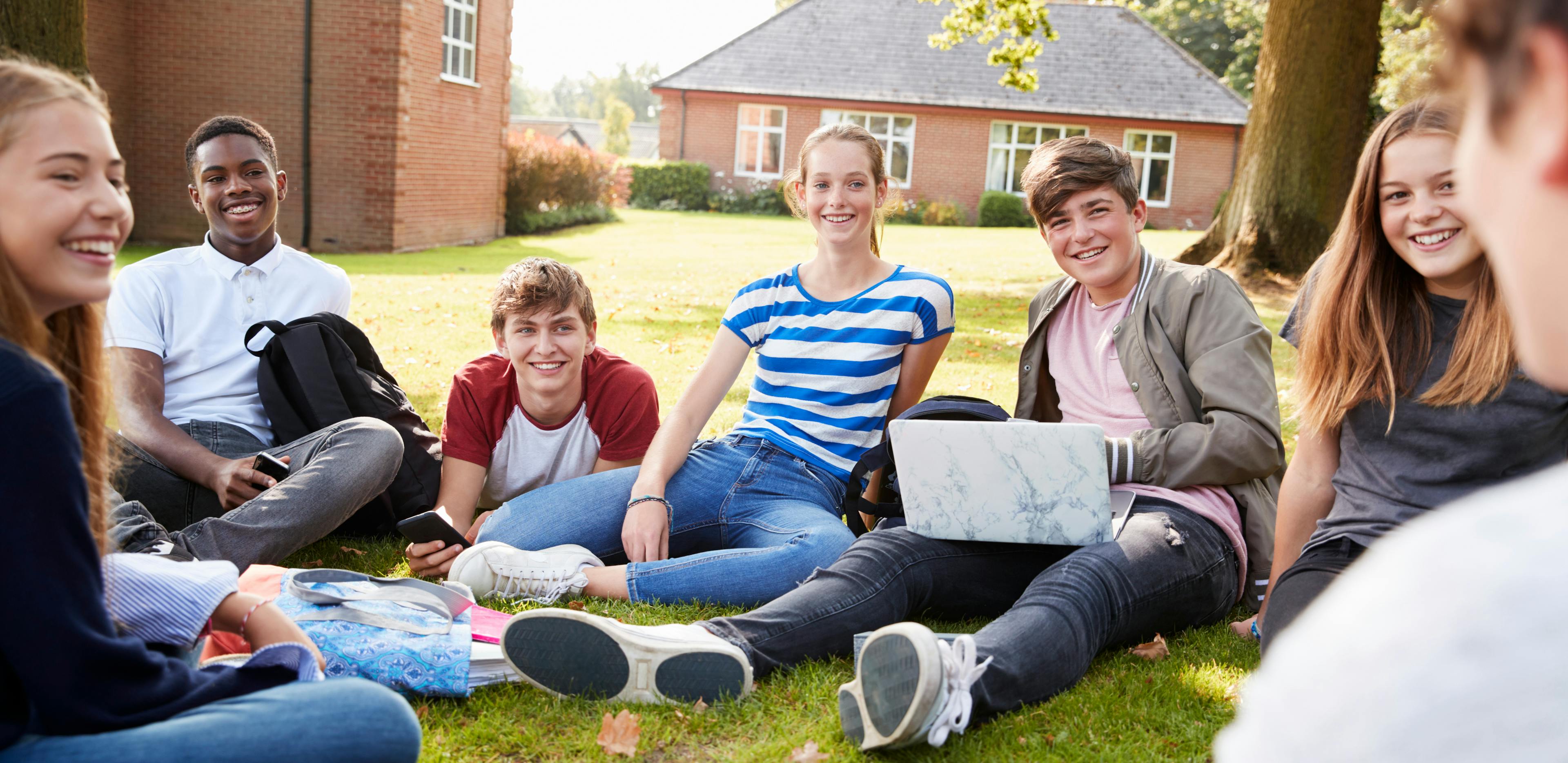 A picture of a diverse group of students sitting in a circle on the grass